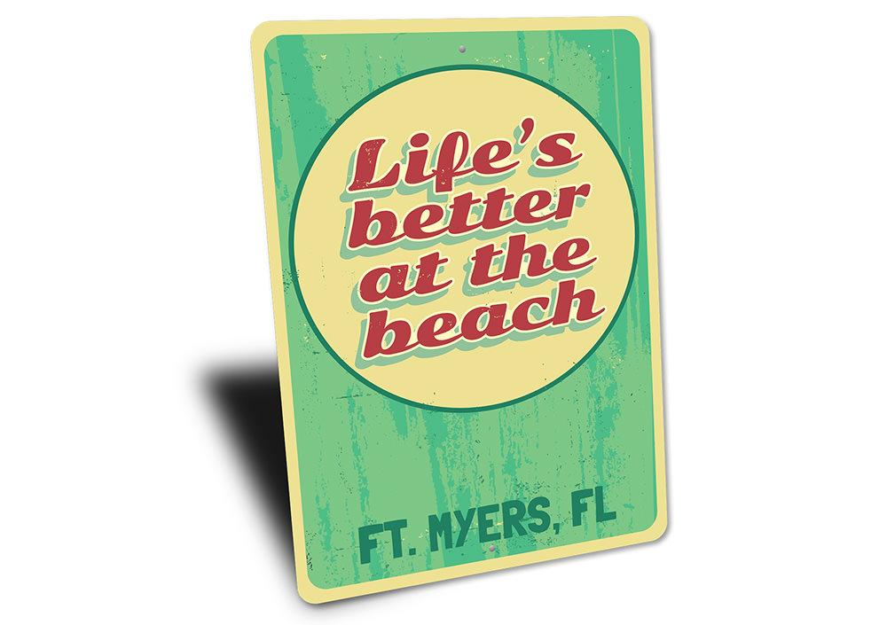 A decorative metal sign reading 'Life is Better at the Beach', featuring a coastal design, perfect for beach houses and seaside decor.