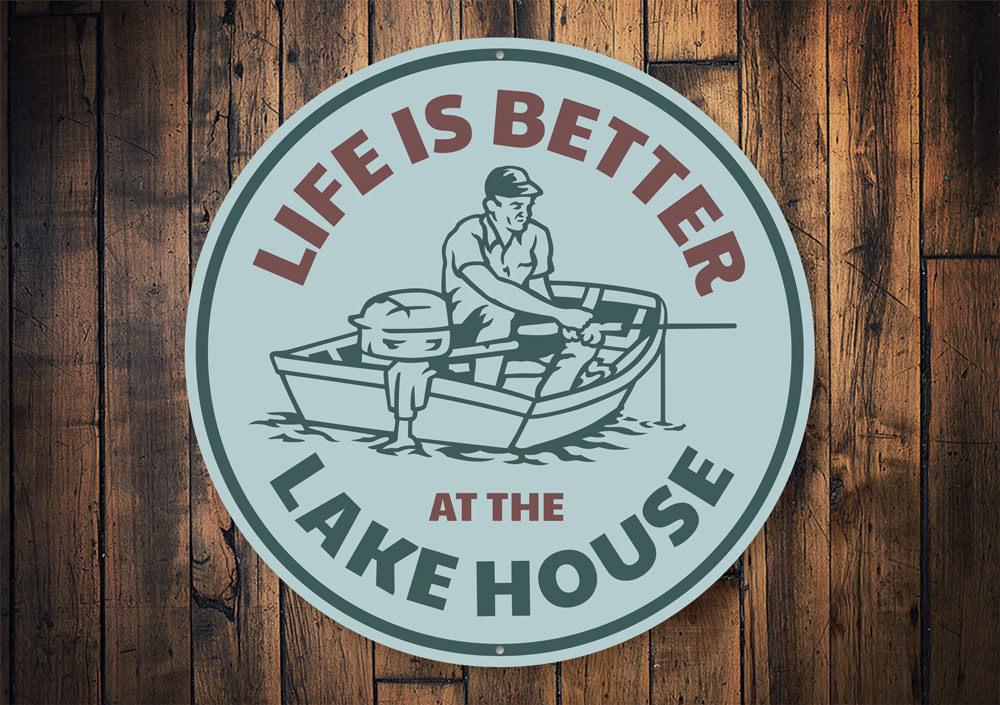 A decorative metal sign reading 'Life is Better at the Lake House', showcasing a beautiful lakeside theme, perfect for home decor.