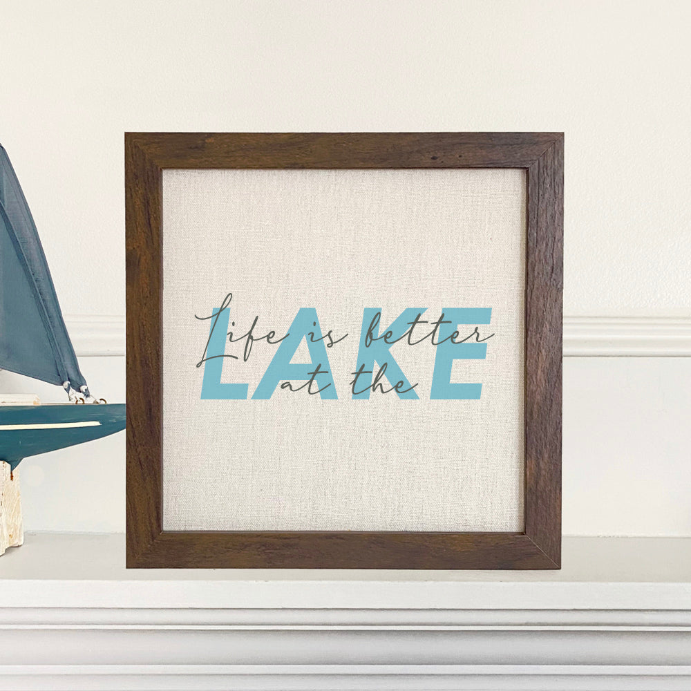 Framed sign reading 'Life is Better at the Lake' with a stylized wood frame, available in walnut or white-washed finish.