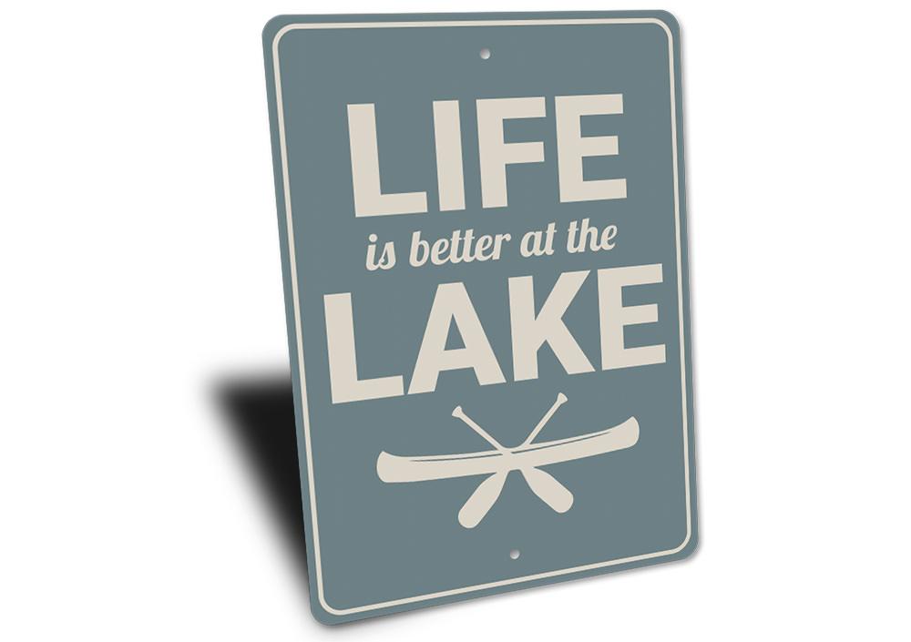 A decorative metal sign reading 'Life is Better at the Lake', showcasing a beautiful lakeside theme, perfect for lakehouses.