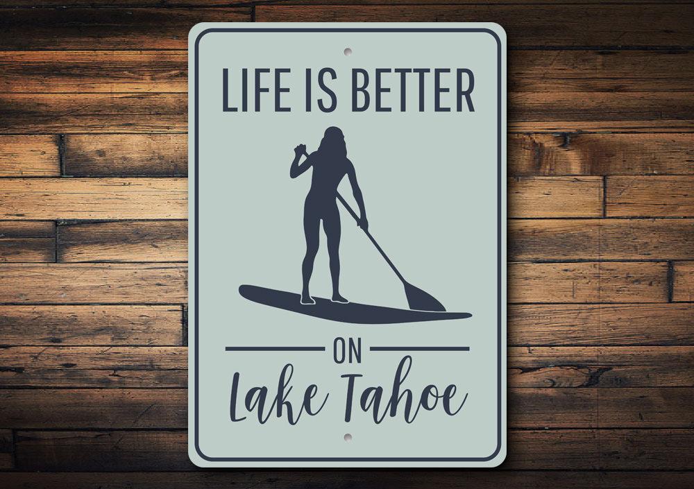 A decorative metal sign that reads 'Life is Better on Lake Tahoe', showcasing a beautiful lake theme, perfect for lakehouse decor.