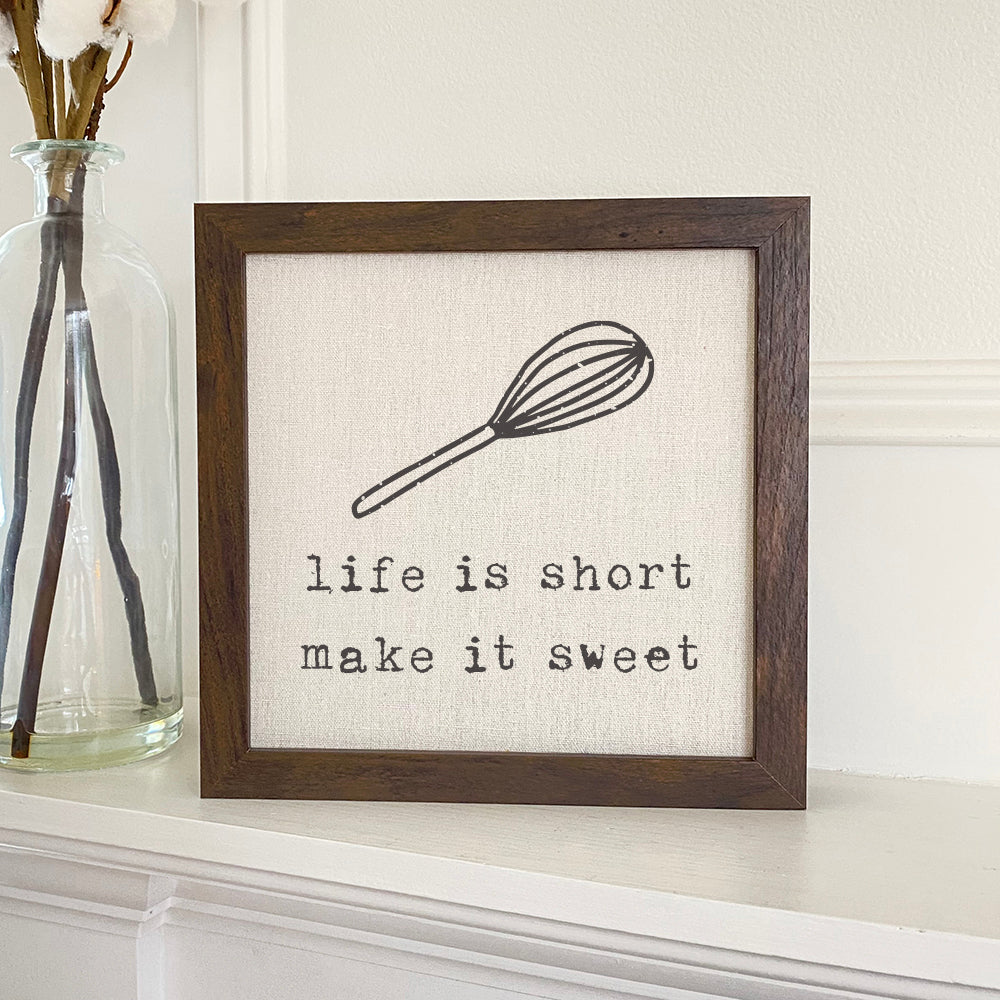 A beautifully framed sign with the text 'Life is Short' on a linen-look background, featuring a rustic wood frame.