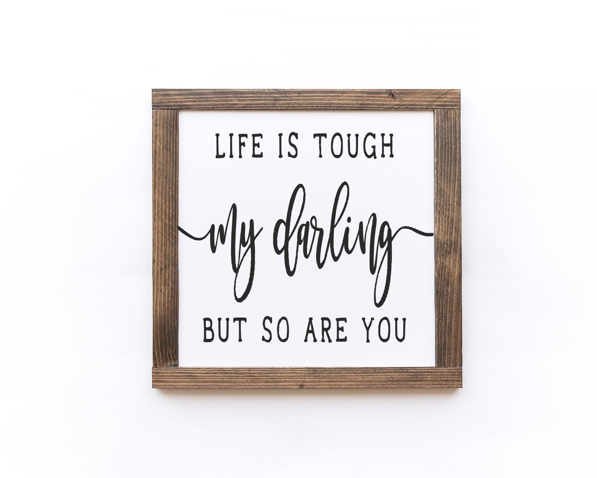 Inspirational wood sign reading 'Life Is Tough My Darling But So Are You', featuring a matte white background and unique wood grain.