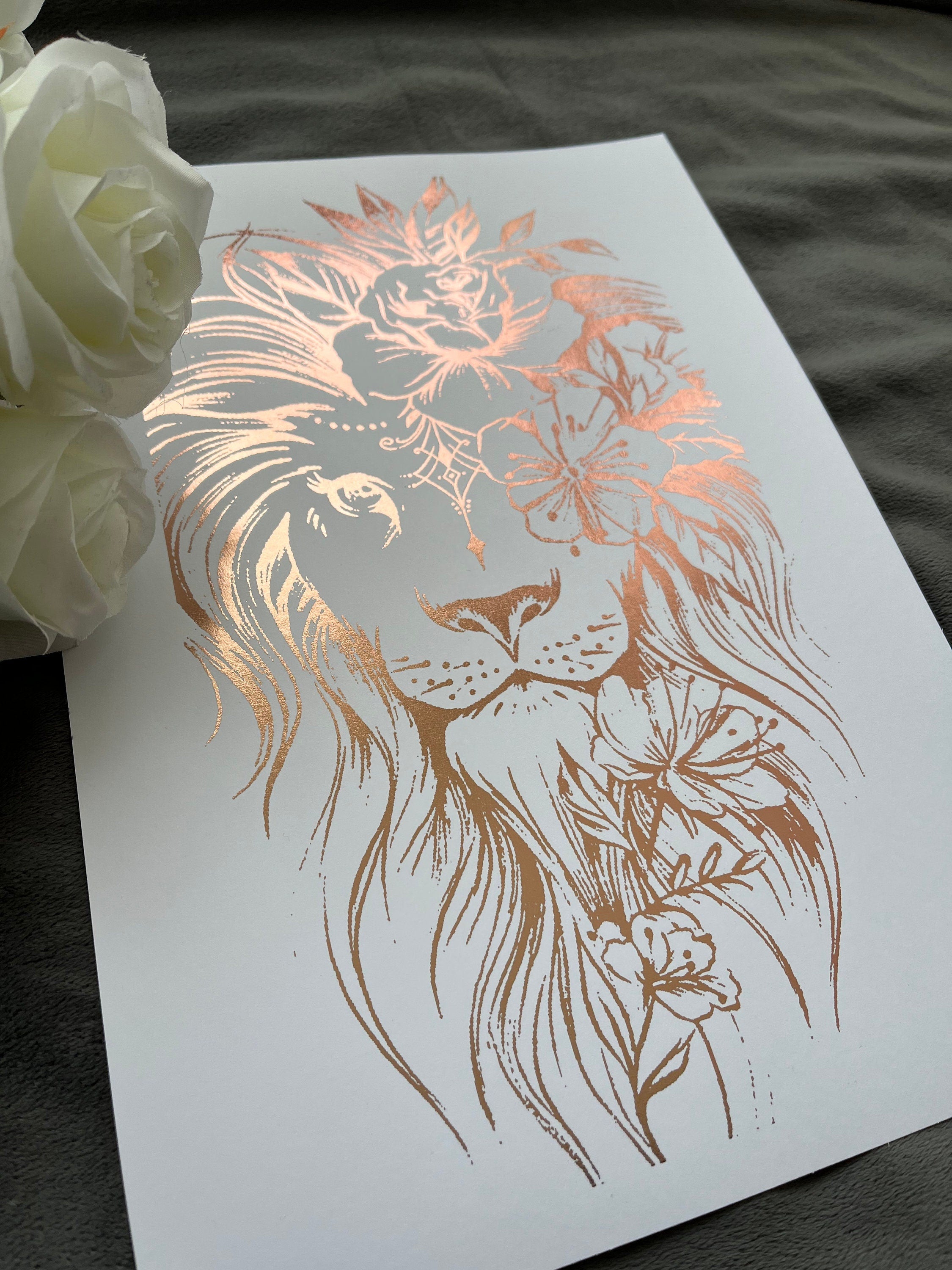 A stunning lion foil print featuring a rose gold lion on a white background, symbolizing courage and strength.