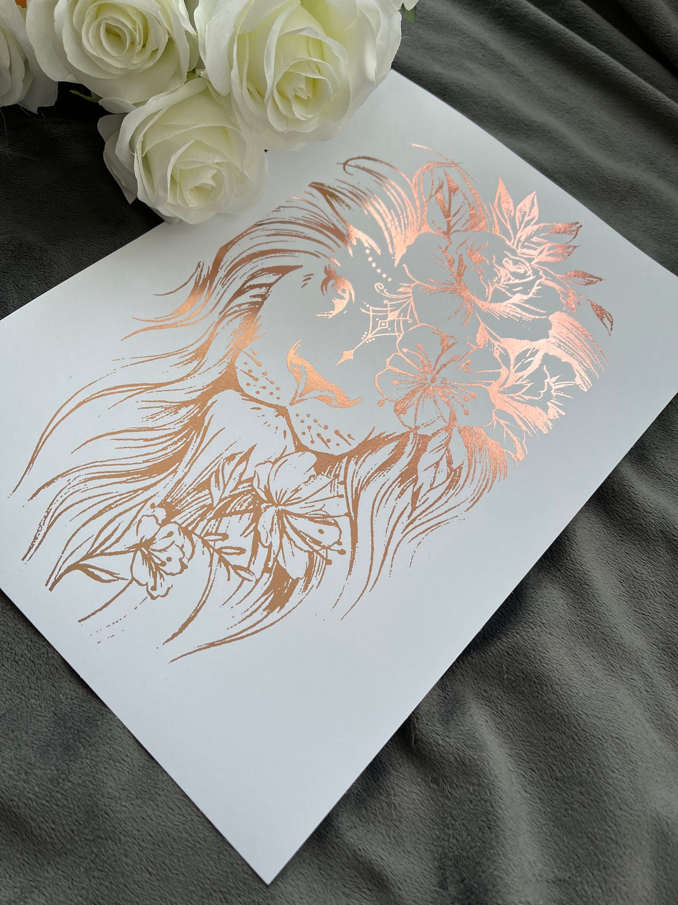 A stunning lion foil print featuring a rose gold lion on a white background, symbolizing courage and strength.