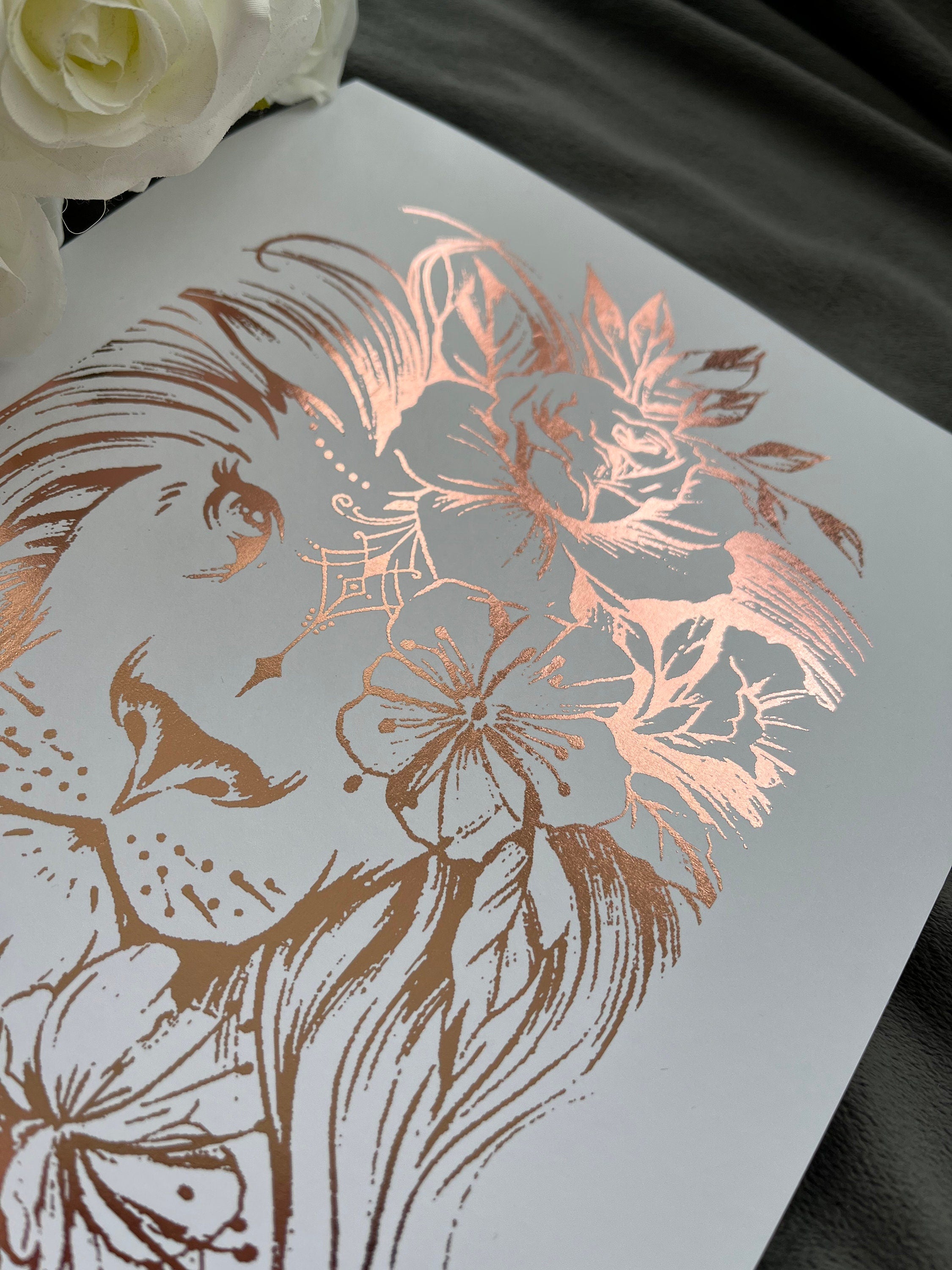 A stunning lion foil print featuring a rose gold lion on a white background, symbolizing courage and strength.