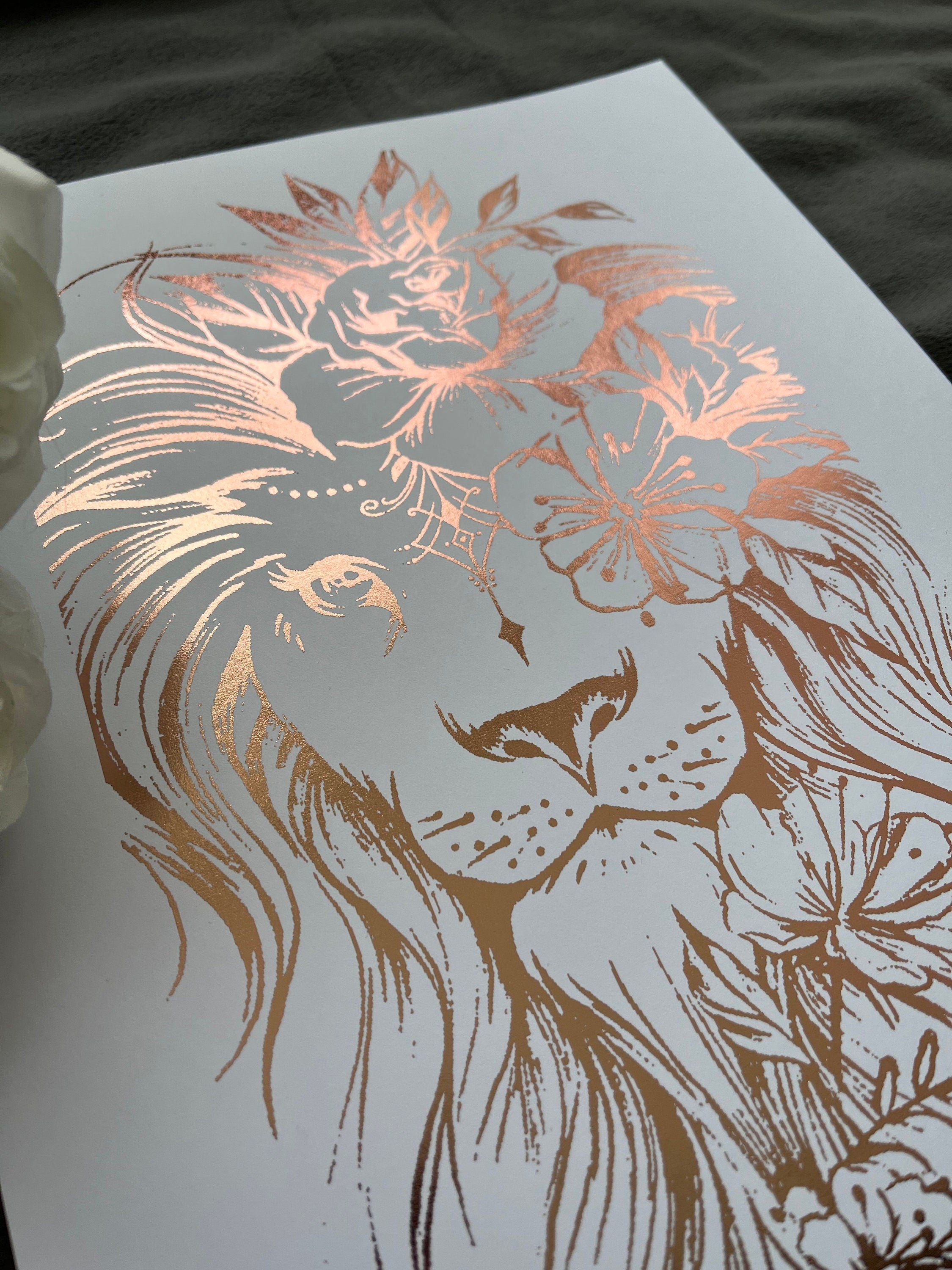 A stunning lion foil print featuring a rose gold lion on a white background, symbolizing courage and strength.