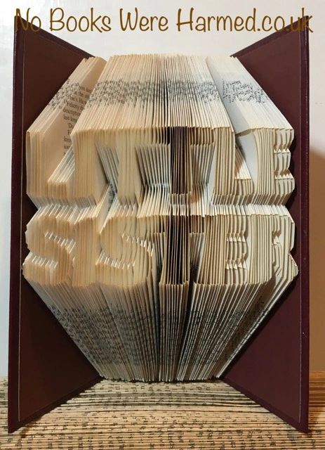 A handcrafted book art piece titled LITTLE SISTER, made from vintage book pages, showcasing intricate folds and unique design.