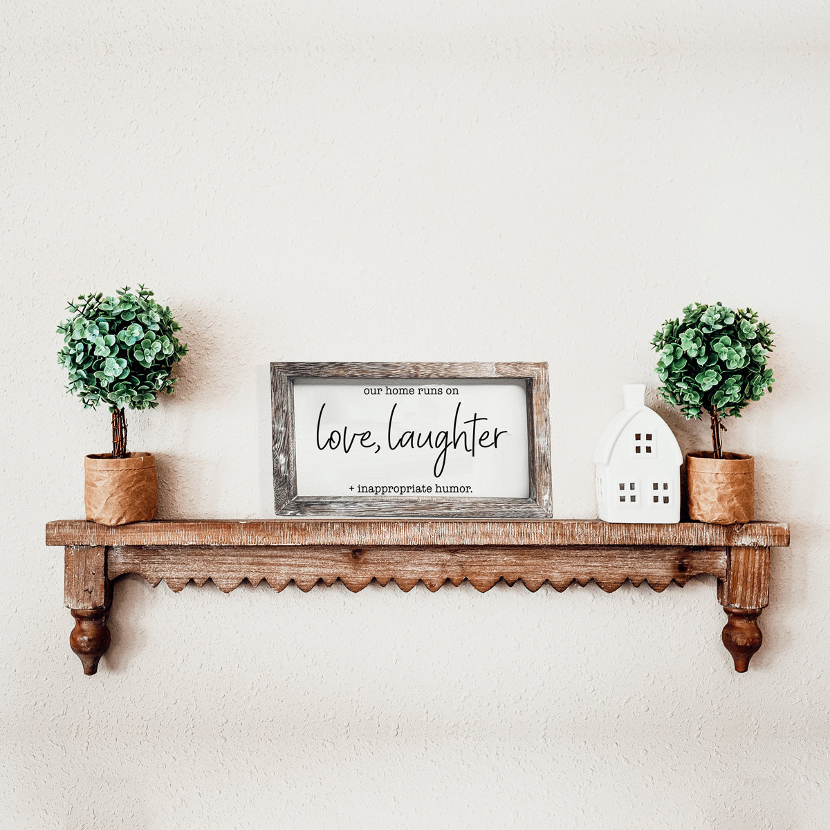 A vintage-style wooden sign that reads 'Our Home Runs on Love, Laughter + Inappropriate Humor', made from durable Paulownia wood.