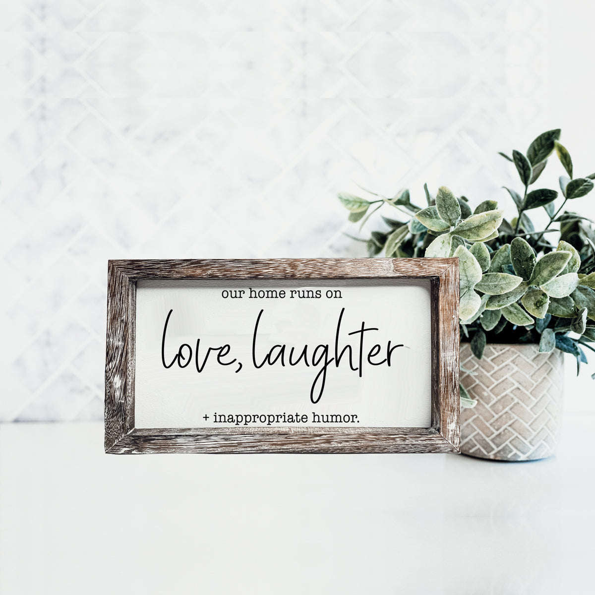 A vintage-style wooden sign that reads 'Our Home Runs on Love, Laughter + Inappropriate Humor', made from durable Paulownia wood.