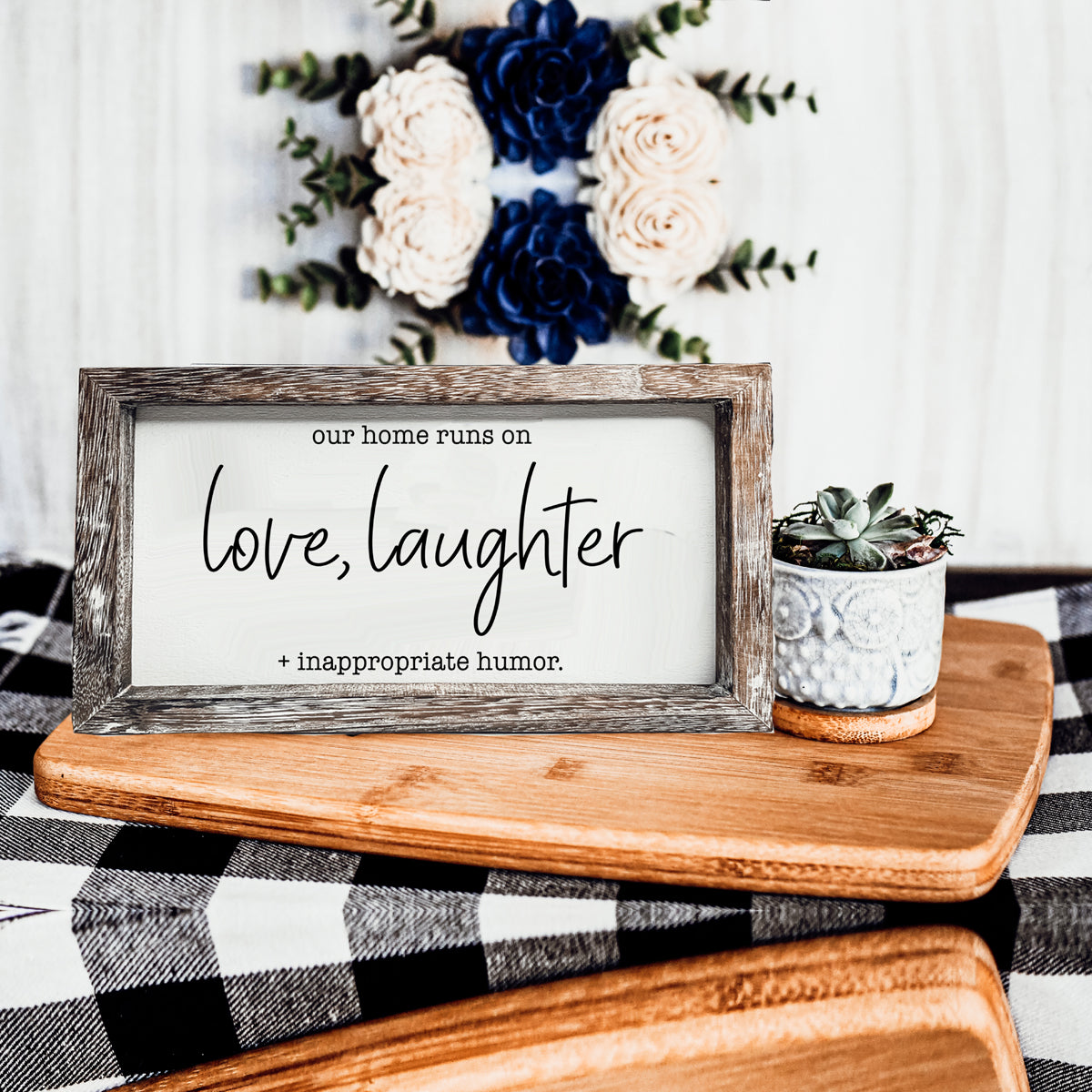 A vintage-style wooden sign that reads 'Our Home Runs on Love, Laughter + Inappropriate Humor', made from durable Paulownia wood.