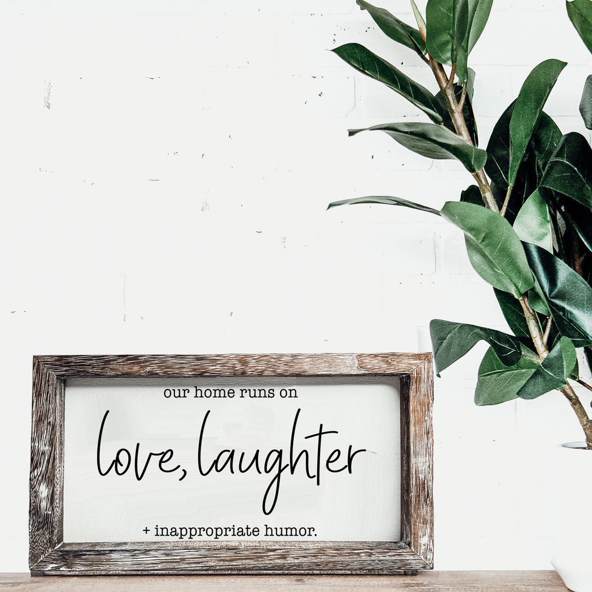 A vintage-style wooden sign that reads 'Our Home Runs on Love, Laughter + Inappropriate Humor', made from durable Paulownia wood.