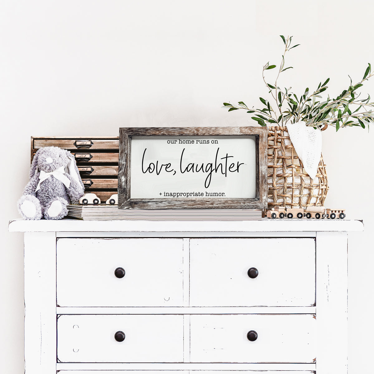 A vintage-style wooden sign that reads 'Our Home Runs on Love, Laughter + Inappropriate Humor', made from durable Paulownia wood.