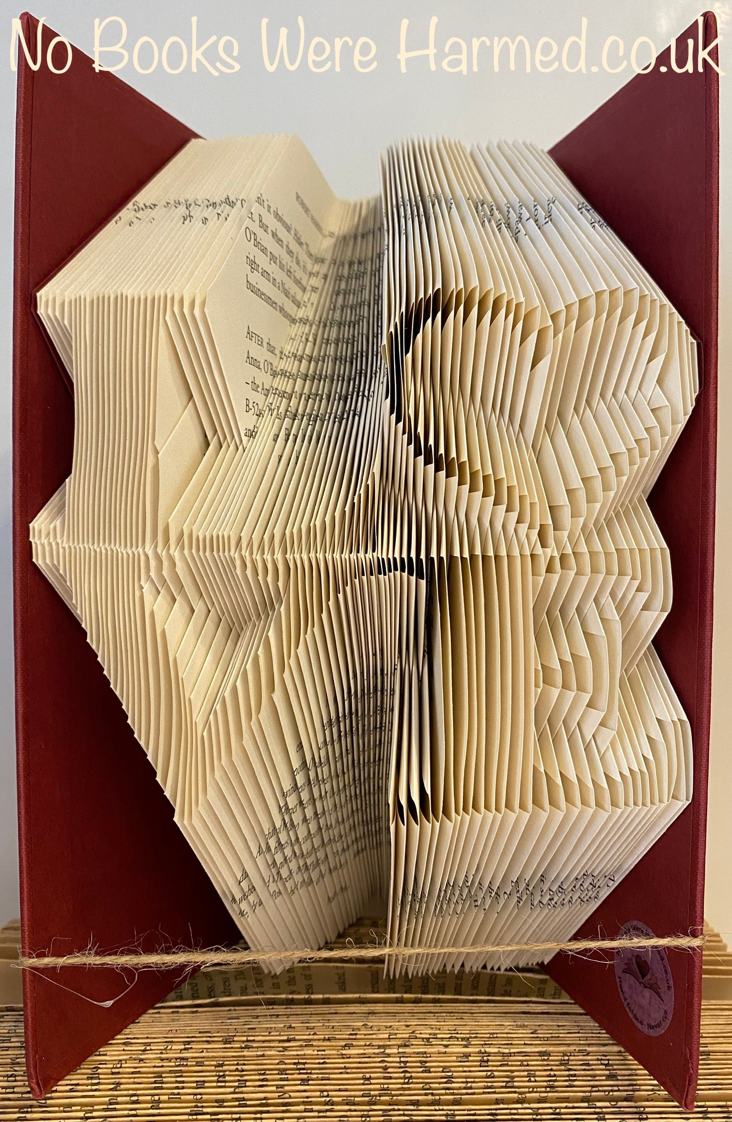 Handcrafted 'Love' square art piece with a hollow heart shape, made from vintage book pages, showcasing unique folds and textures.