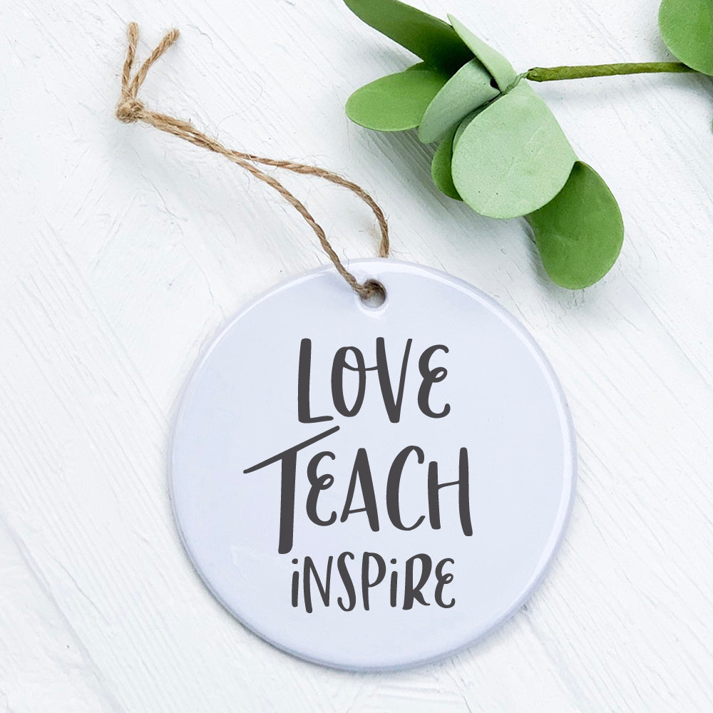 A beautifully designed porcelain ornament featuring the words 'Love Teach Inspire', showcasing vibrant colors and a smooth finish.