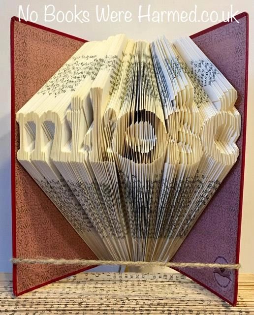 Hand folded book art displaying the word 'miłość' in Polish, crafted from vintage pages, showcasing unique folds and textures.