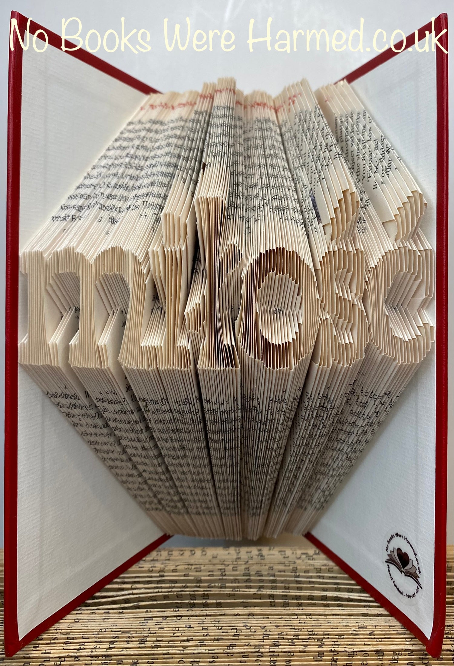 Hand folded book art displaying the word 'miłość' in Polish, crafted from vintage pages, showcasing unique folds and textures.