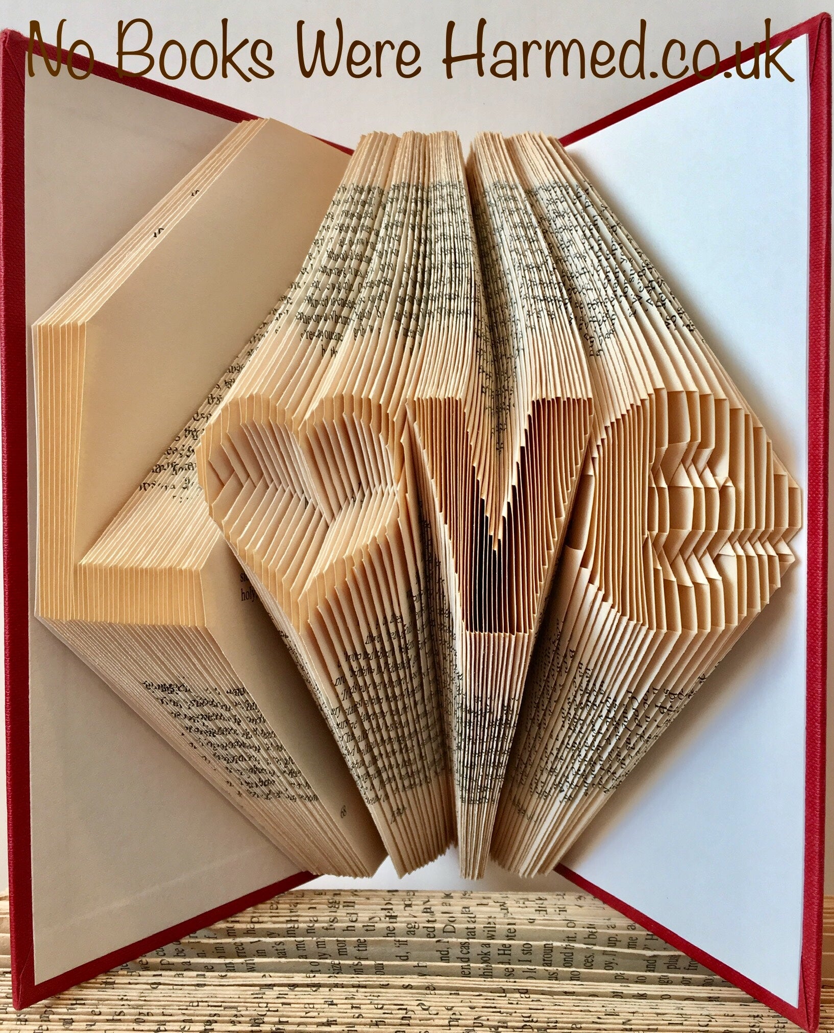 Unique hand-folded book art piece titled L♥ve, crafted from vintage books with intricate folds and varying colors.