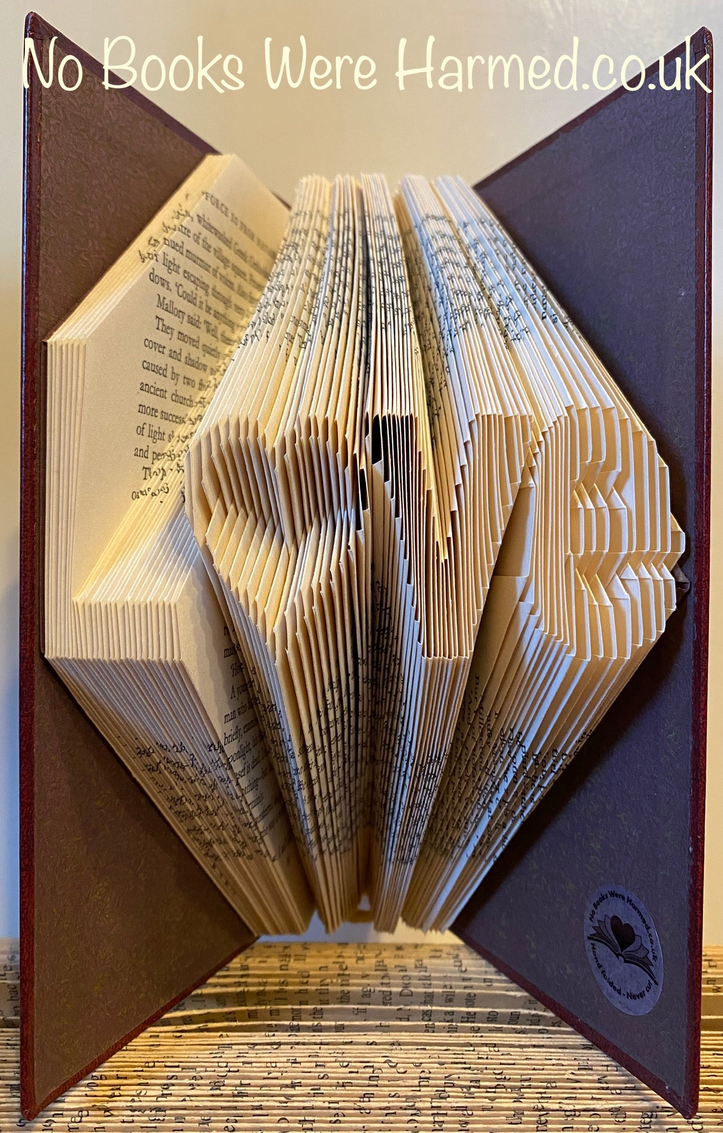 Unique hand-folded book art piece titled L♥ve, crafted from vintage books with intricate folds and varying colors.