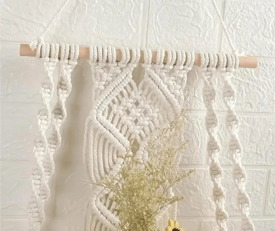 A beautifully handcrafted Macrame Wall Tapestry Plant Holder made from cotton cords, featuring a natural wooden shelf for plants or books.