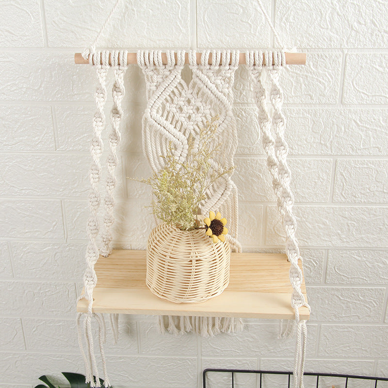 A beautifully handcrafted Macrame Wall Tapestry Plant Holder made from cotton cords, featuring a natural wooden shelf for plants or books.