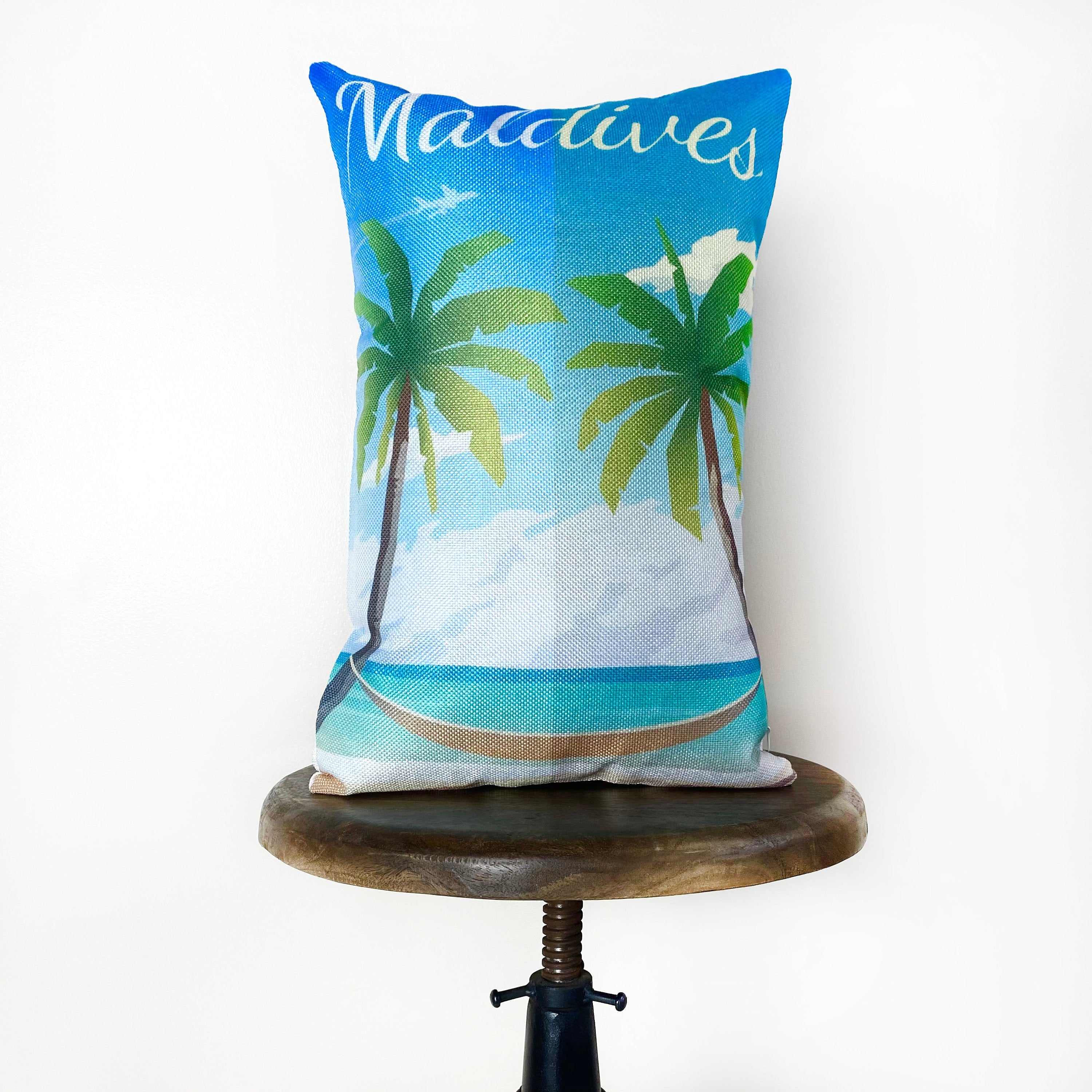 A vibrant 12x18 pillow cover featuring a travel poster of a beach in the Maldives, showcasing tropical colors and a concealed zipper.