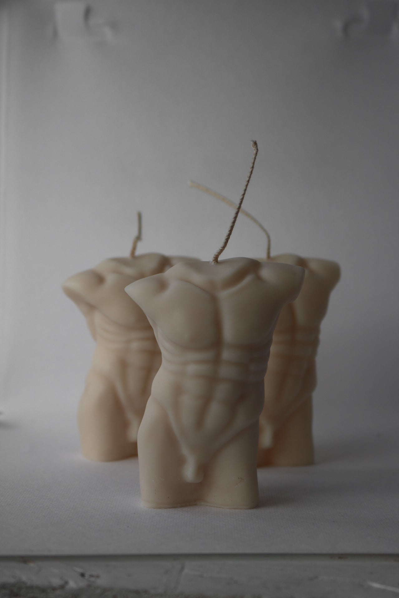 A beautifully crafted Male torso candle in soft cream/white color, showcasing intricate details and a sculptural design, perfect for home decor.