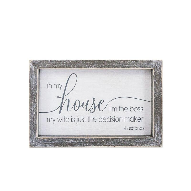 A humorous wooden sign that reads 'In My House I'm The Boss, My Wife Is Just The Decision Maker - Husbands', framed in white and grey.