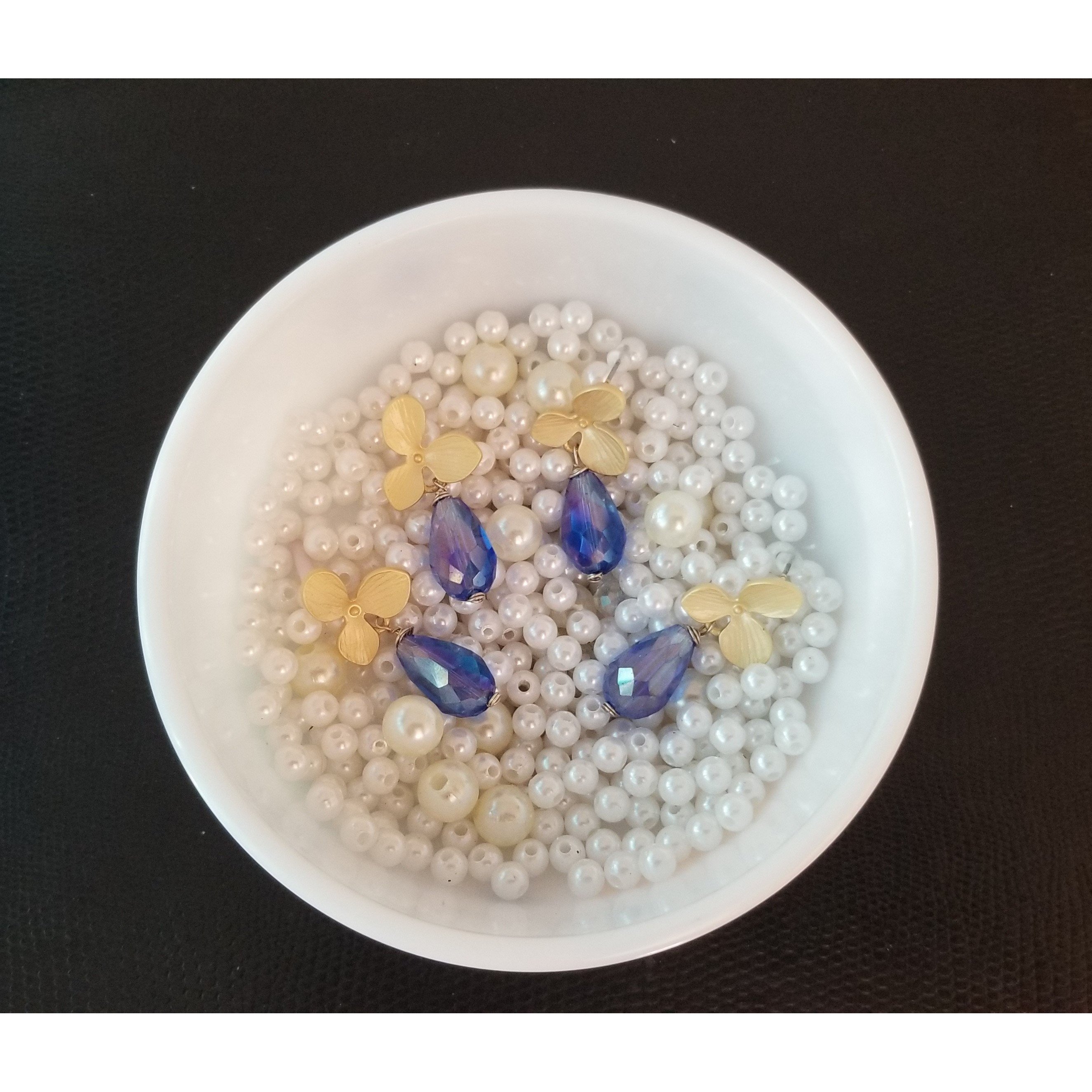 Matte golden flower earrings with blue crystal teardrop beads, showcasing intricate floral design and elegant color contrast.