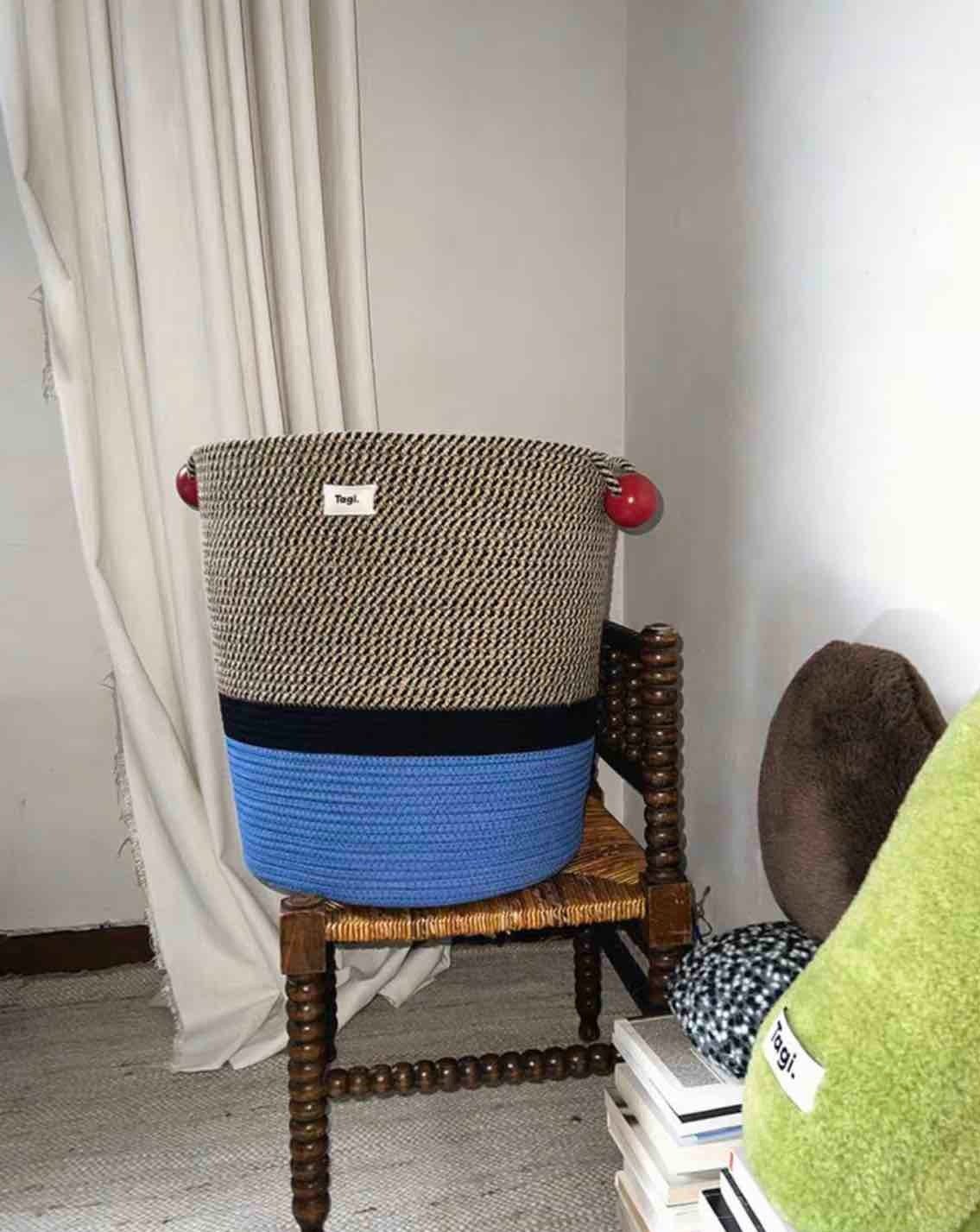 Colorful handmade woven laundry storage basket with comfortable handles, showcasing maximalism design.