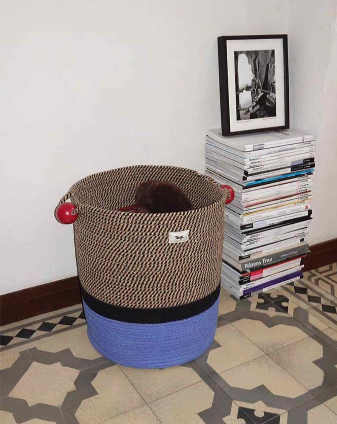 Colorful handmade woven laundry storage basket with comfortable handles, showcasing maximalism design.