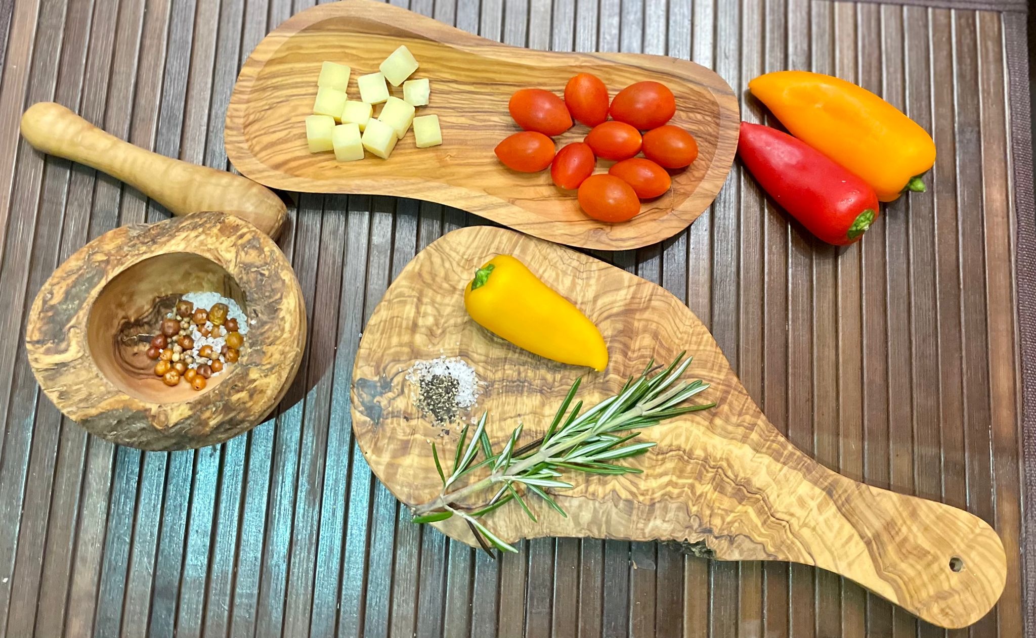 Mediterranean Olive Wood Collection featuring a mortar and pestle, multi-purpose bowl, and cutting board, showcasing beautiful grain patterns.