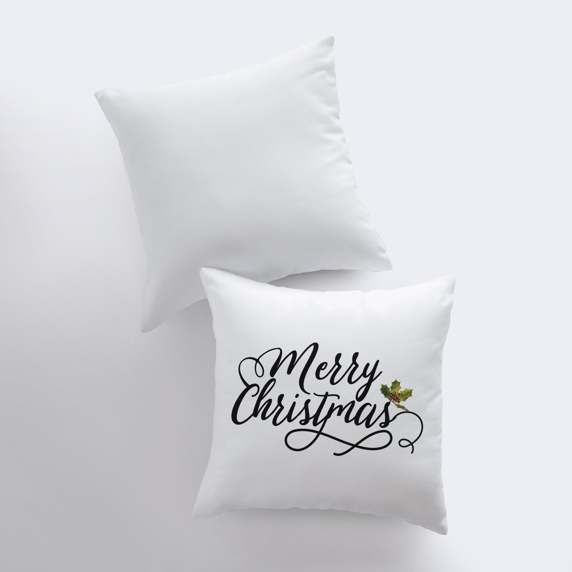 Merry Christmas throw pillow featuring black cursive lettering on a white background with a holly twig accent, perfect for holiday decor.