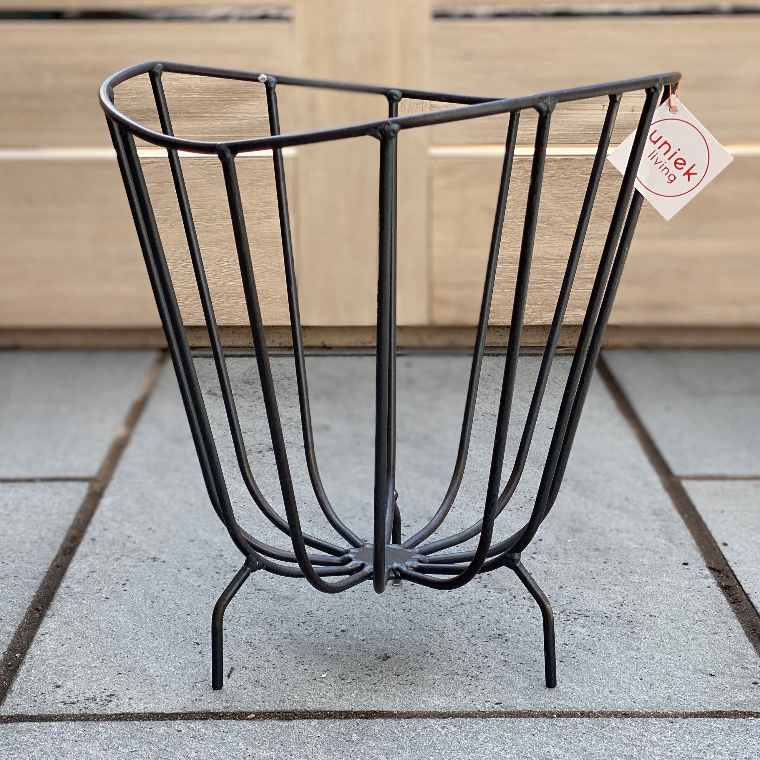 A modern handmade metal basket by K'WILLEM IN HUIS, crafted from recycled round iron with a powder-coated finish, showcasing its stylish design and multiple color options.