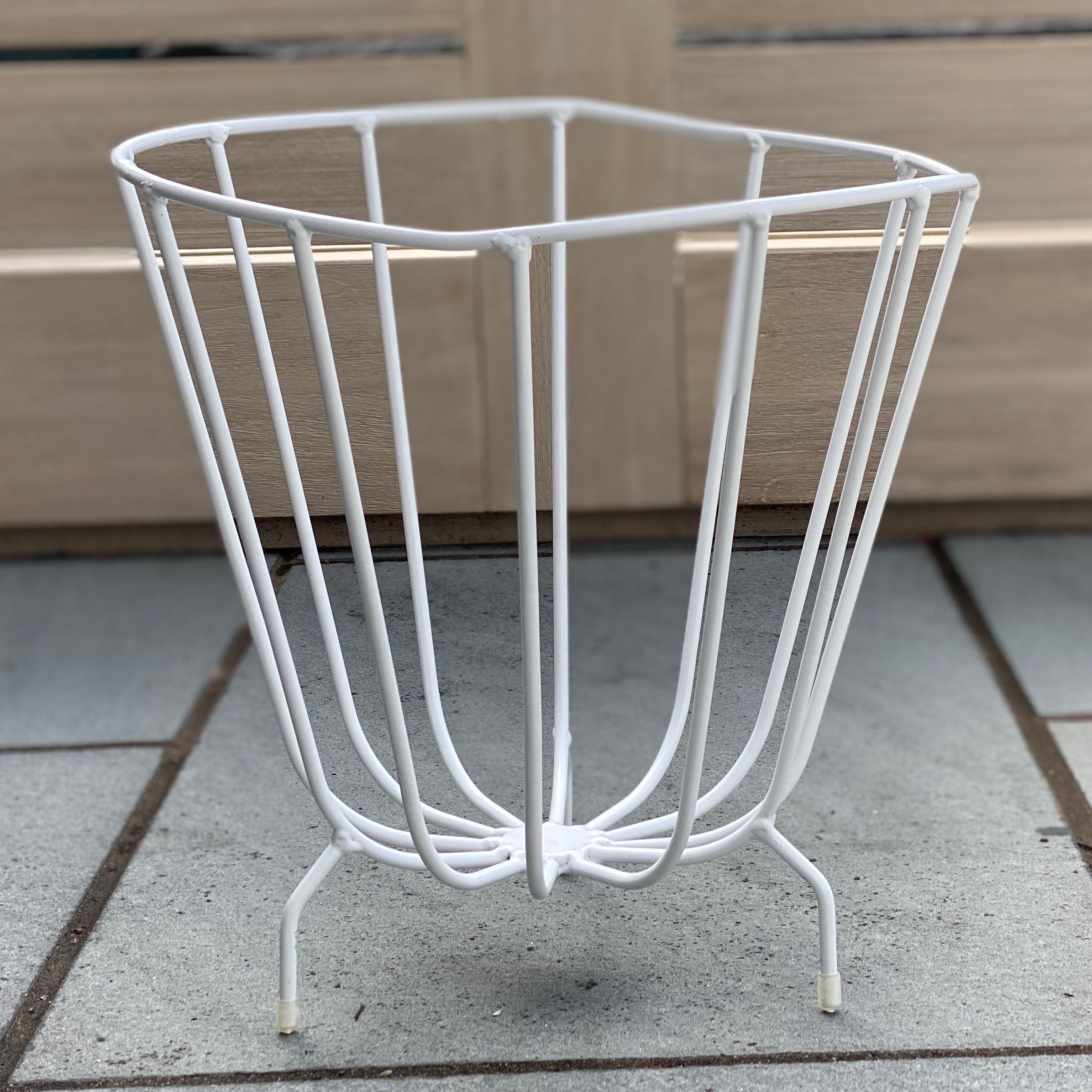 A modern handmade metal basket by K'WILLEM IN HUIS, crafted from recycled round iron with a powder-coated finish, showcasing its stylish design and multiple color options.