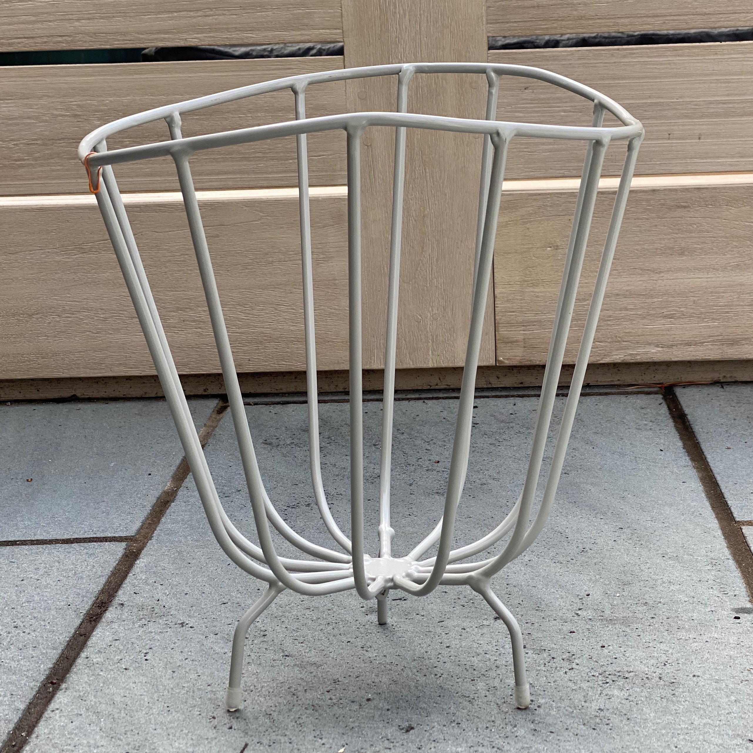 A modern handmade metal basket by K'WILLEM IN HUIS, crafted from recycled round iron with a powder-coated finish, showcasing its stylish design and multiple color options.