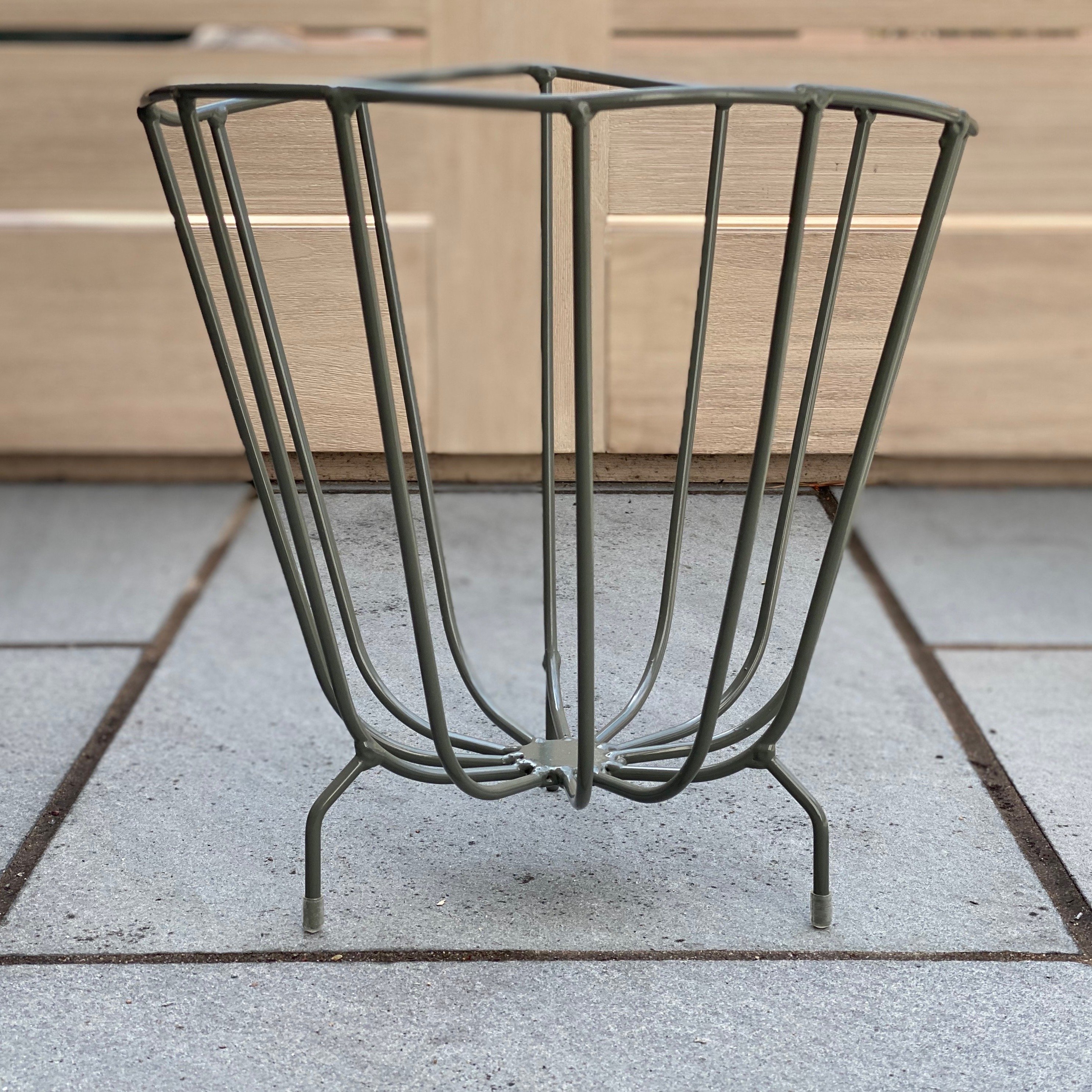 A modern handmade metal basket by K'WILLEM IN HUIS, crafted from recycled round iron with a powder-coated finish, showcasing its stylish design and multiple color options.