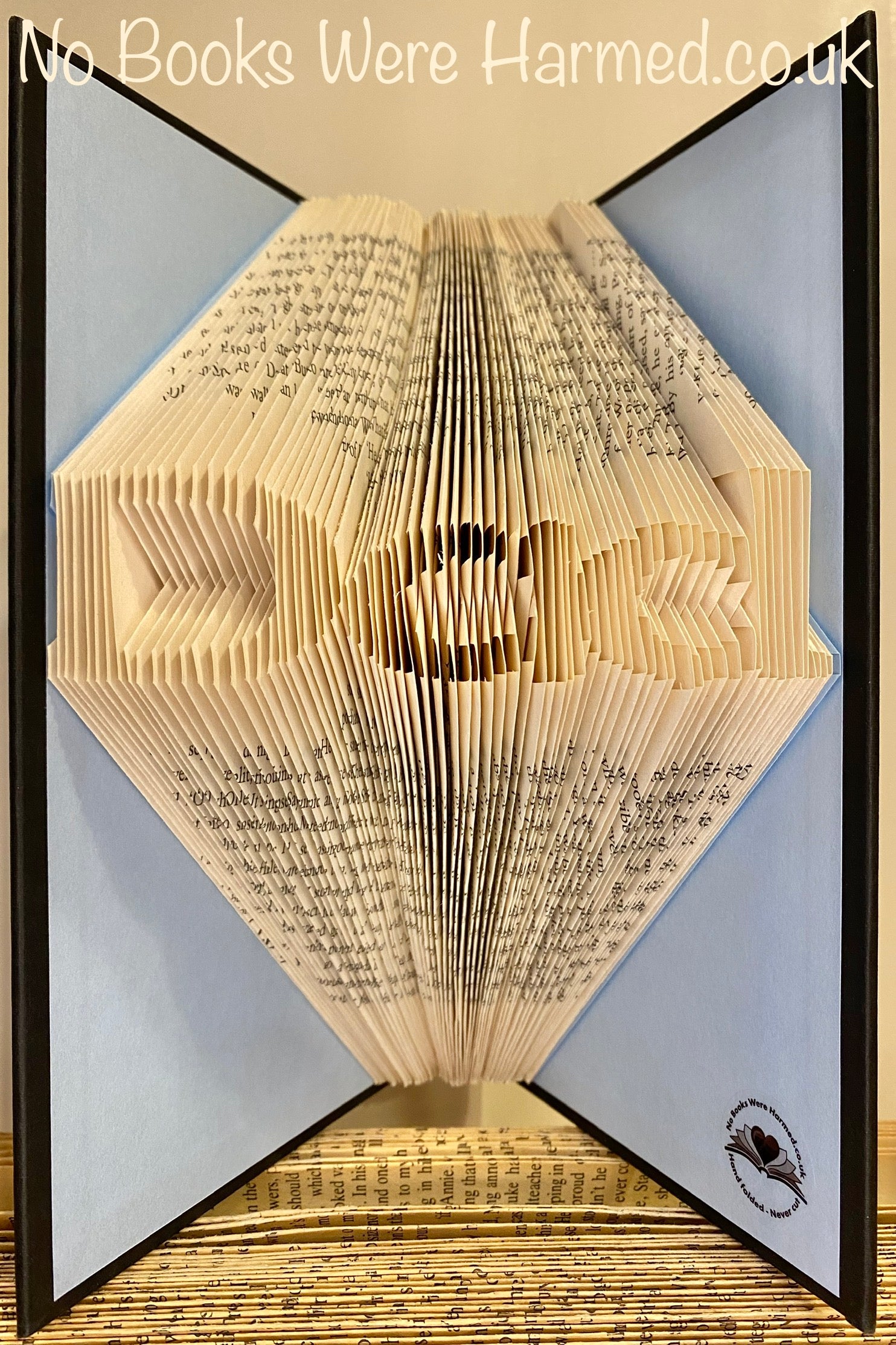 Mini 'Dad' art piece handcrafted from vintage book pages, showcasing intricate folds and unique design.