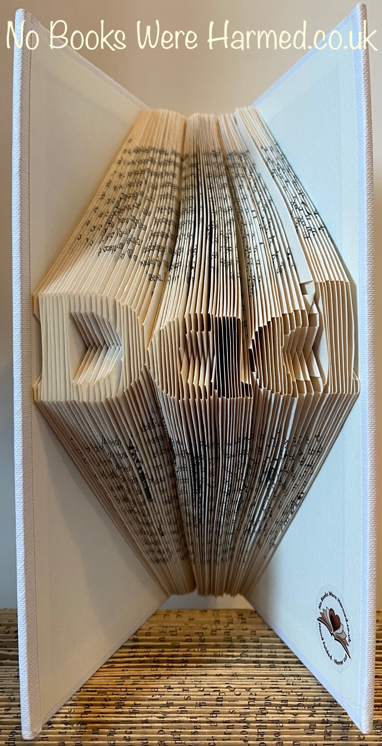 Mini 'Dad' art piece handcrafted from vintage book pages, showcasing intricate folds and unique design.