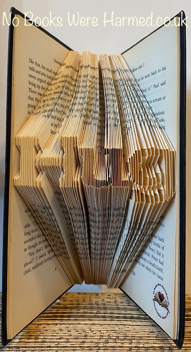 A handcrafted mini 'Hug' art piece made from folded pages of vintage books, showcasing intricate designs and unique colors.