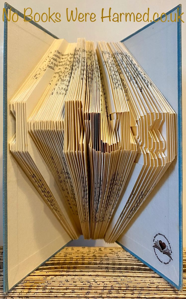 A handcrafted mini 'Hug' art piece made from folded pages of vintage books, showcasing intricate designs and unique colors.