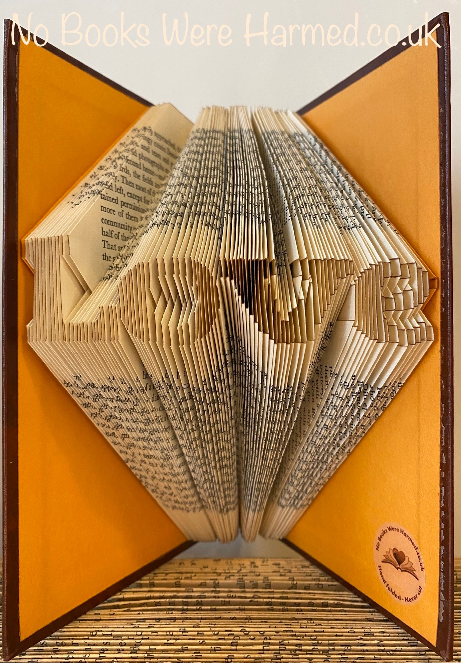 A handcrafted mini 'Love' art piece made from vintage book pages, showcasing intricate folds and unique design.