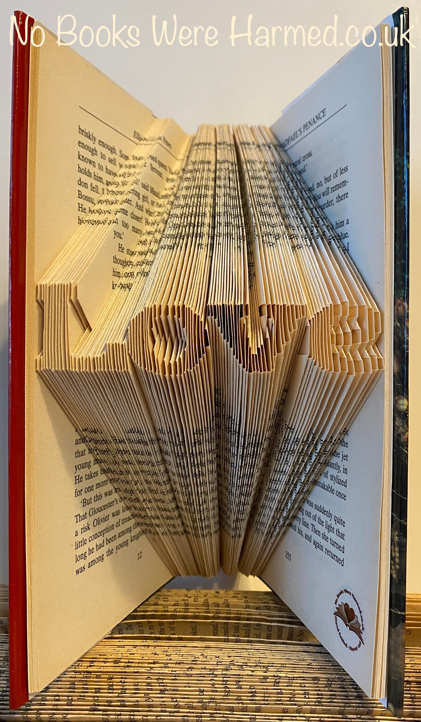 A handcrafted mini 'Love' art piece made from vintage book pages, showcasing intricate folds and unique design.