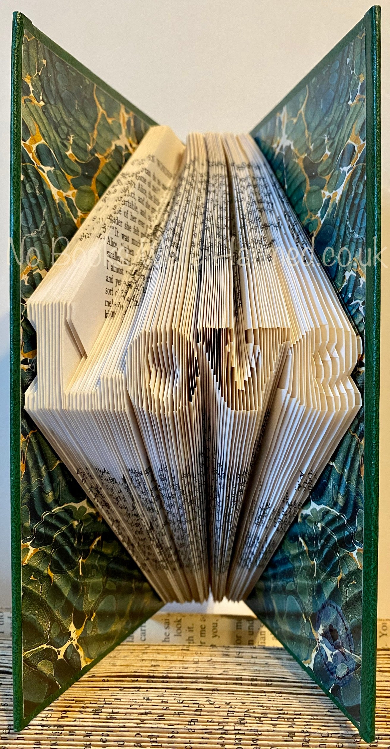 A handcrafted mini 'Love' art piece made from vintage book pages, showcasing intricate folds and unique design.