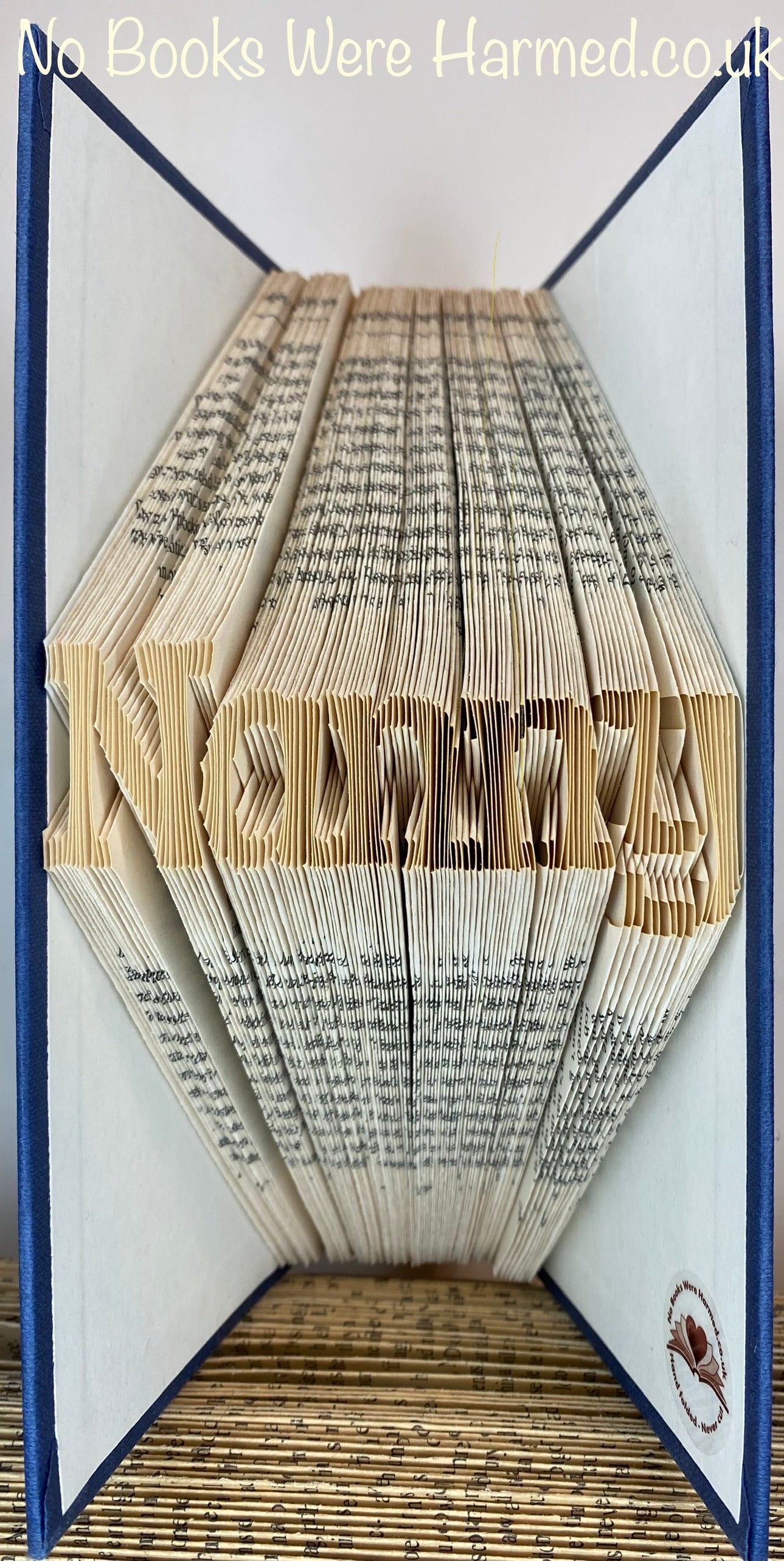 Mini 'Nanny' art piece handcrafted from vintage books, showcasing intricate hand-folded designs.