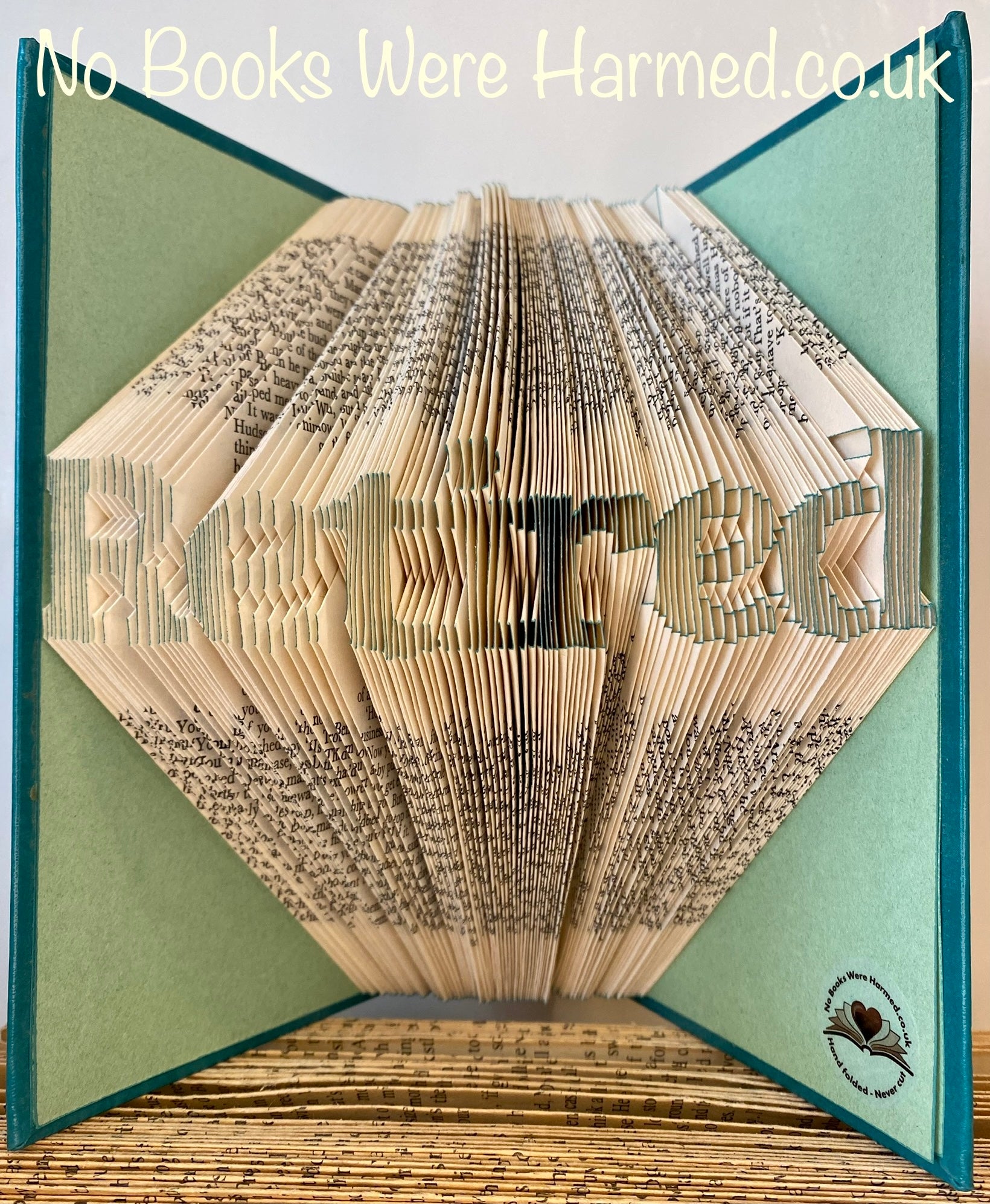 Mini 'Retired' art piece handcrafted from vintage book pages, showcasing unique folds and colors.