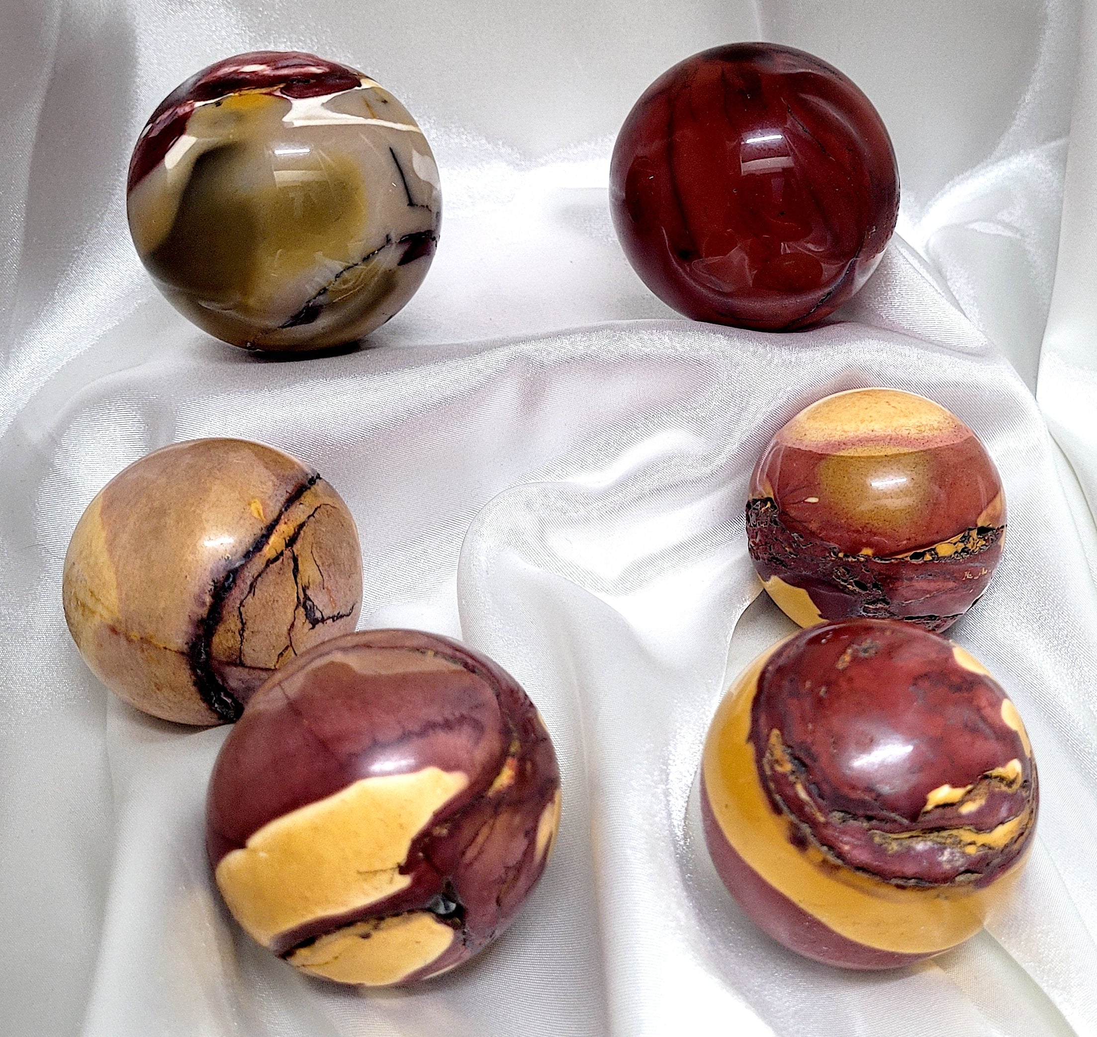 A beautifully hand-carved Mookaite Jasper Sphere showcasing vibrant colors of red, yellow, and brown, symbolizing its unique healing properties.