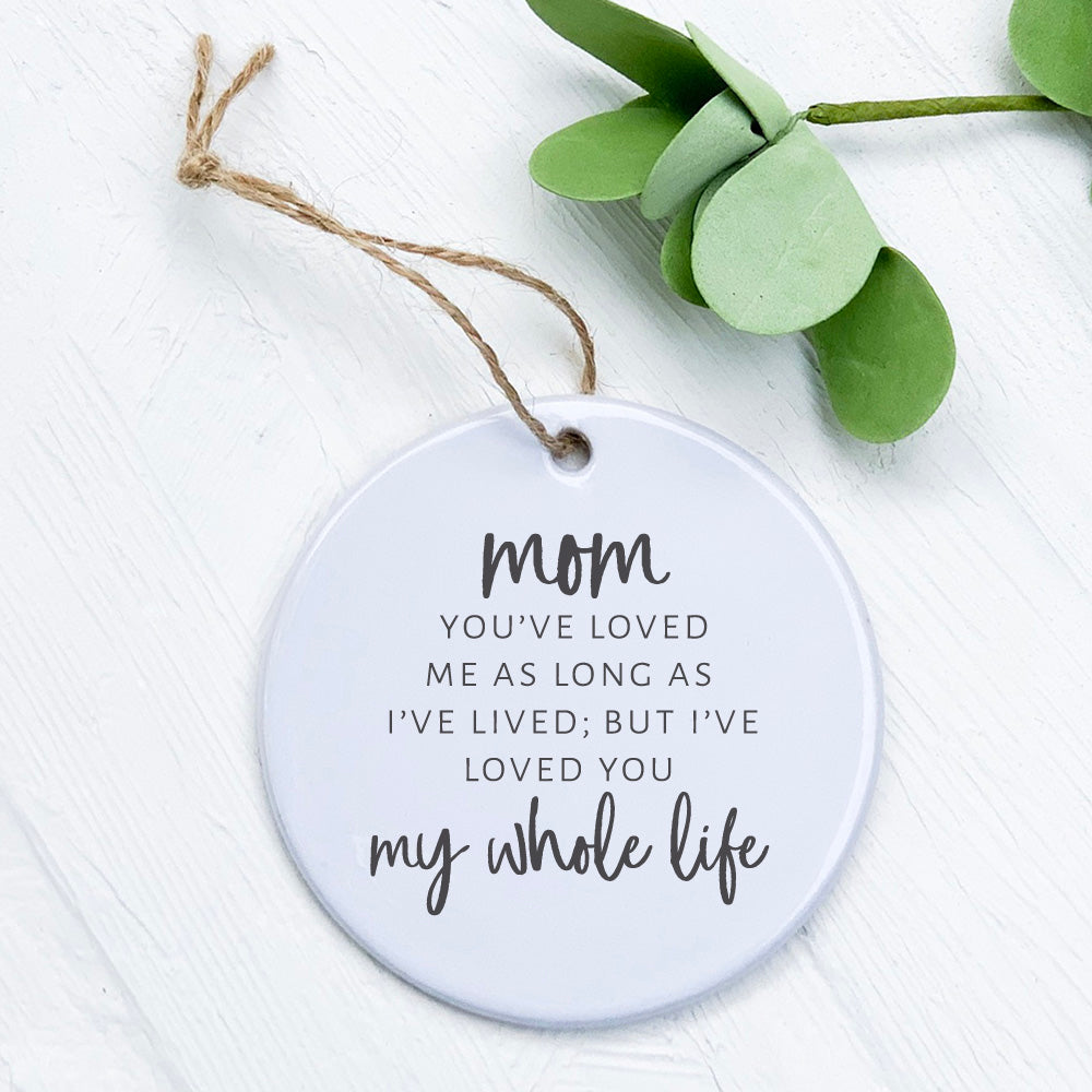 A beautiful porcelain ornament featuring the phrase 'Mom / Mommy Loved You My Whole Life', showcasing a smooth, glossy finish.