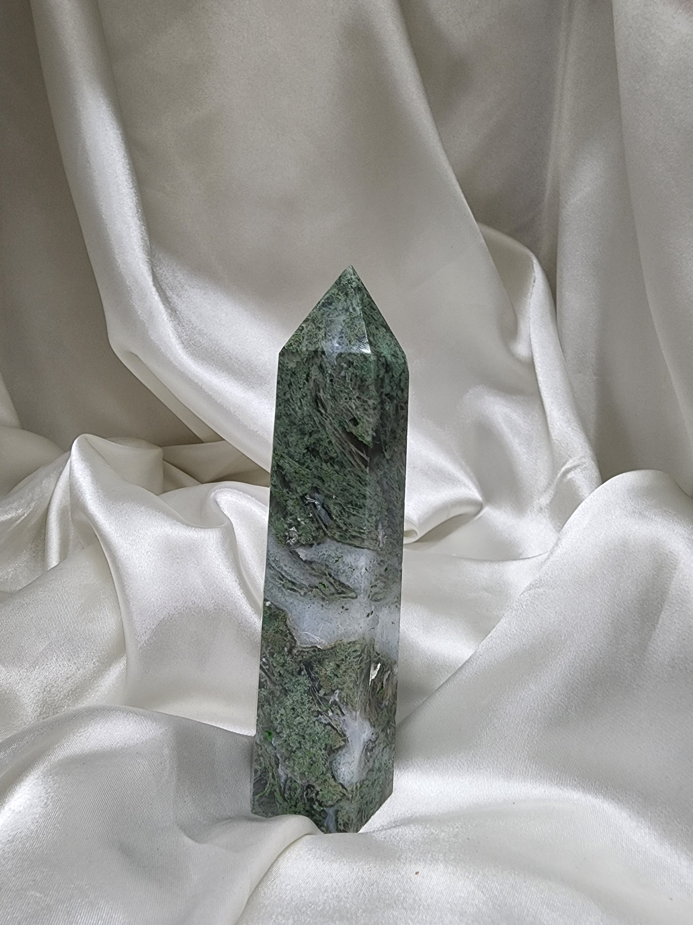 A beautifully hand-carved Moss Agate Generator showcasing its unique green and earthy patterns, symbolizing strength and grounding energy.