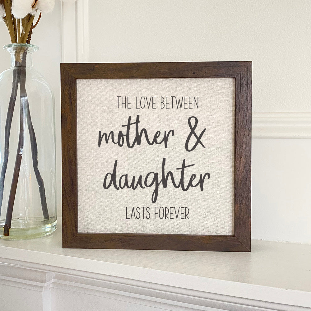 Framed sign featuring 'Mother Daughter Love' with a stylish wood frame, available in walnut or white-washed finish.